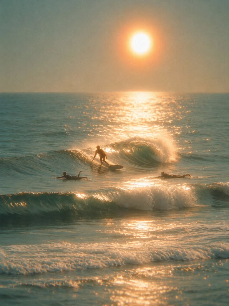 Surfers riding a wave at sunset